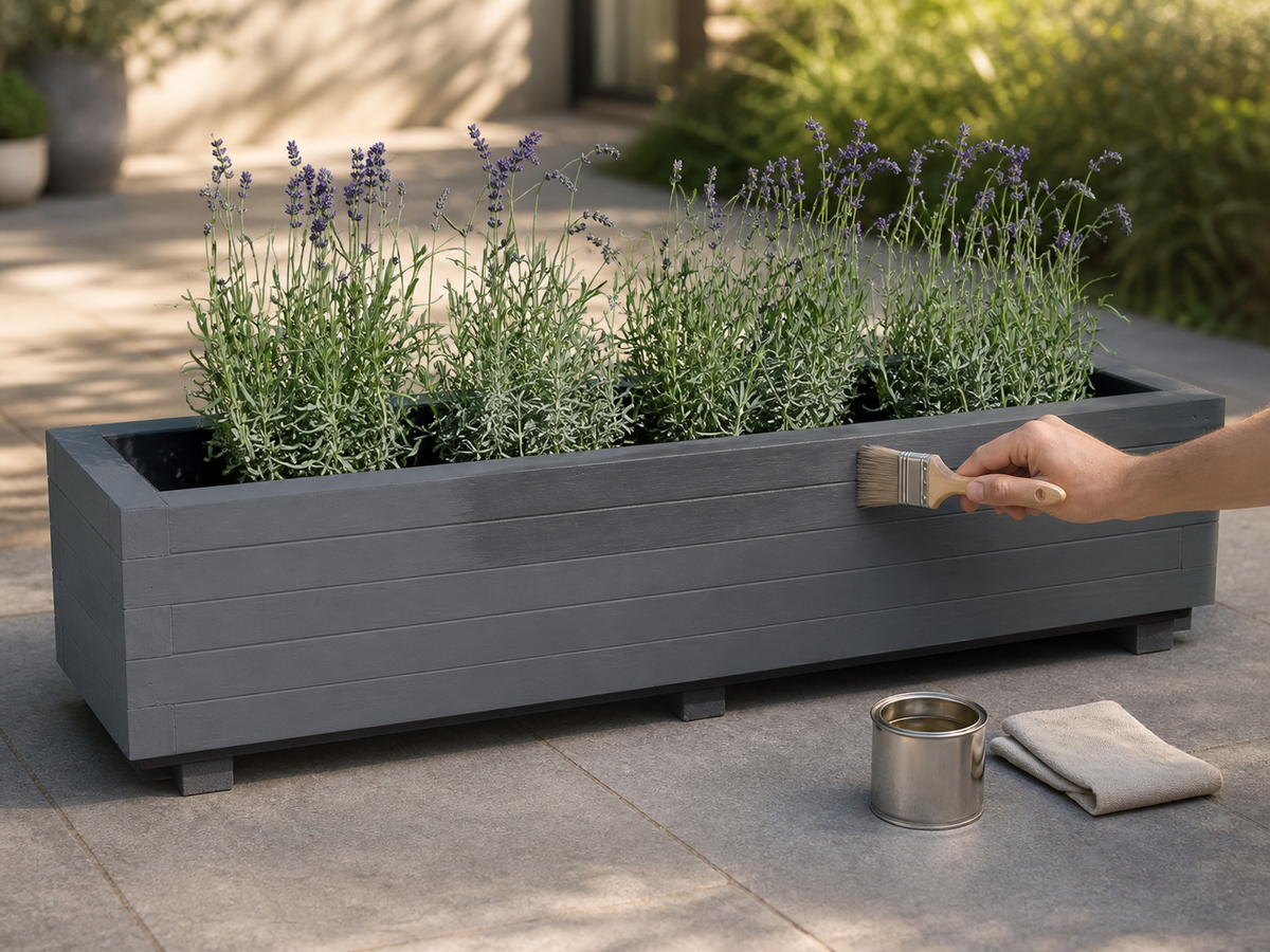 Antraciete houten plantenbak met lavendel wordt met een kwast behandeld met houtolie